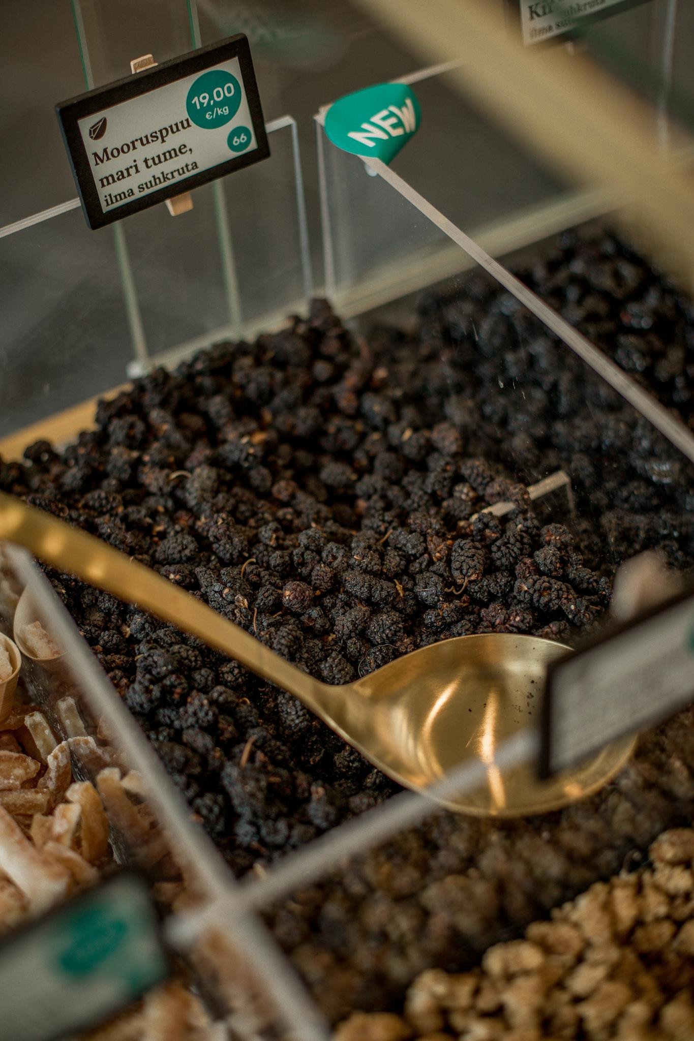 Close-up of assorted spices in a market bin with a golden ladle for serving.